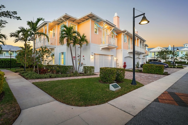 view of front of house with a yard, a balcony, and a garage