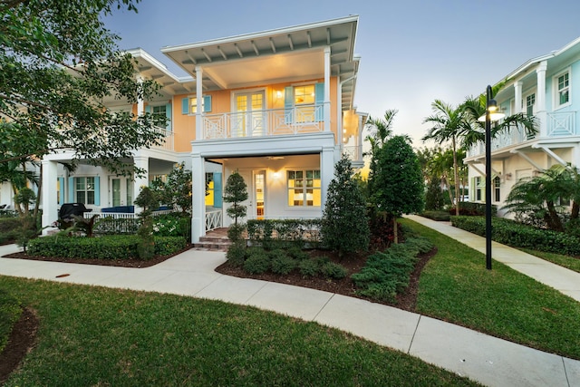 view of front of home with a yard, a balcony, and covered porch