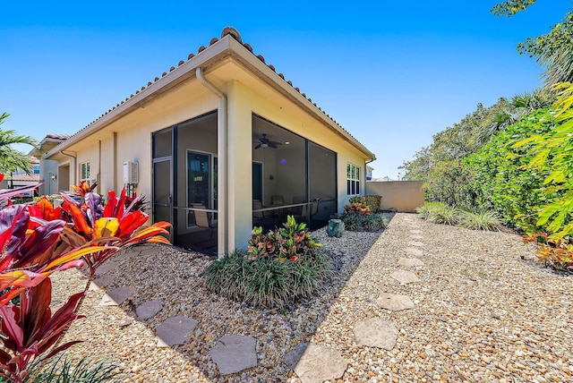 view of side of property featuring a sunroom and ceiling fan