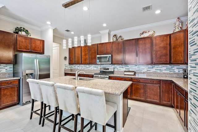 kitchen featuring pendant lighting, a kitchen bar, a kitchen island with sink, and appliances with stainless steel finishes