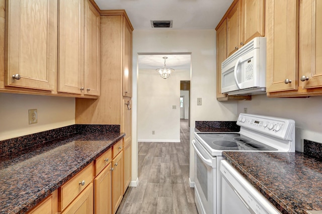 kitchen featuring white appliances, pendant lighting, a notable chandelier, dark stone countertops, and light hardwood / wood-style floors