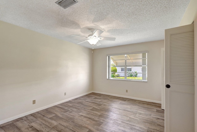 spare room with ceiling fan, light hardwood / wood-style floors, and a textured ceiling