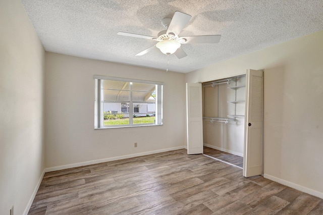 unfurnished bedroom featuring ceiling fan, a closet, light hardwood / wood-style floors, and a textured ceiling