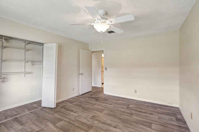 unfurnished bedroom featuring ceiling fan, a closet, hardwood / wood-style floors, and a textured ceiling