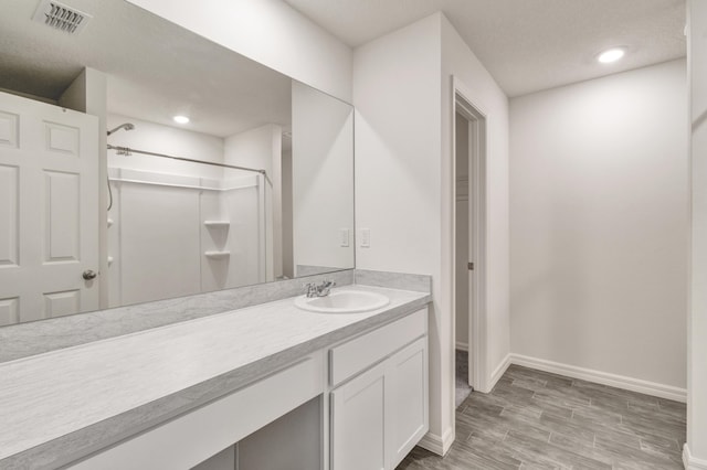 bathroom with a shower, hardwood / wood-style floors, and vanity