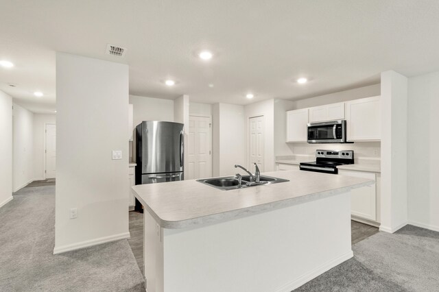 kitchen with sink, an island with sink, light colored carpet, white cabinets, and appliances with stainless steel finishes