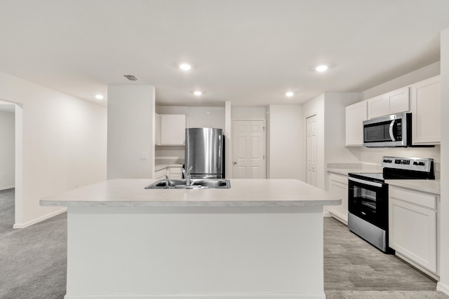 kitchen featuring a kitchen island with sink, white cabinets, sink, light colored carpet, and stainless steel appliances