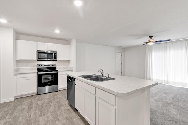 kitchen with appliances with stainless steel finishes, ceiling fan, sink, white cabinets, and an island with sink