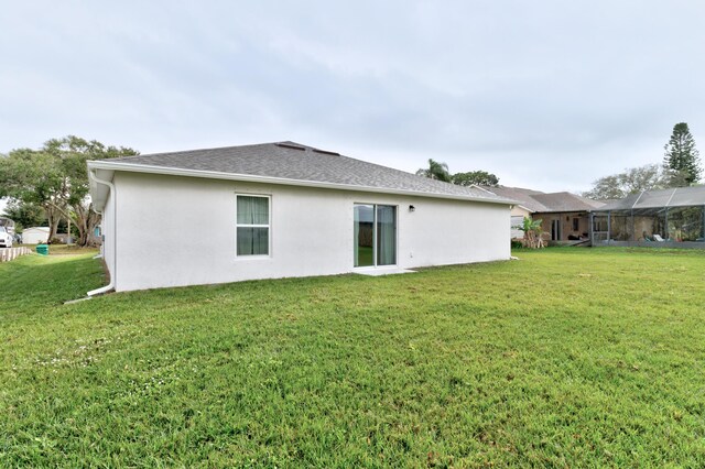 rear view of house featuring a lanai and a lawn