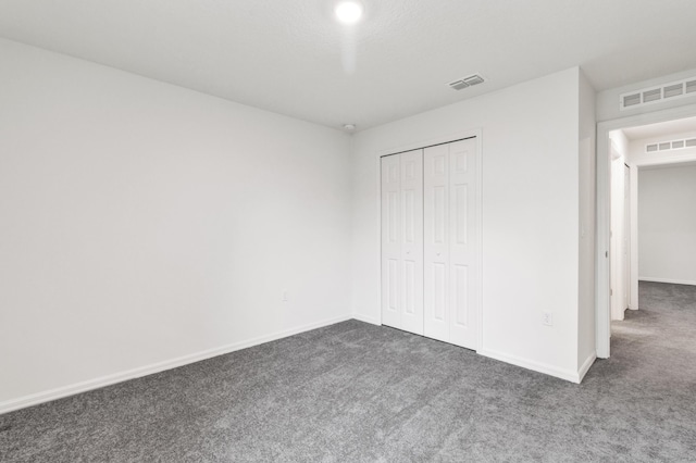 unfurnished bedroom with dark colored carpet and a closet