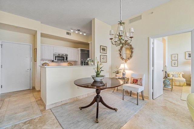 kitchen featuring kitchen peninsula, a chandelier, pendant lighting, decorative backsplash, and white cabinets