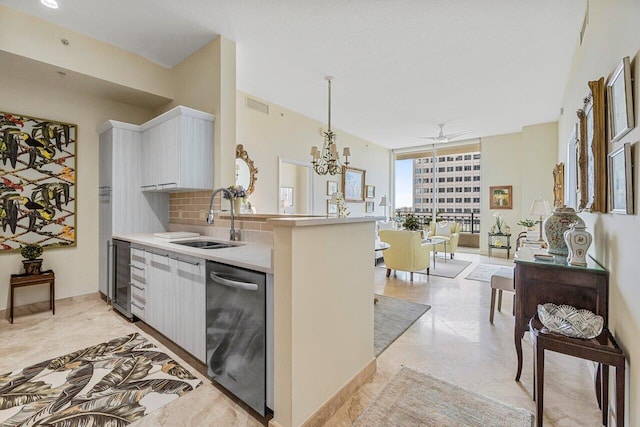 kitchen with pendant lighting, ceiling fan with notable chandelier, sink, wine cooler, and tasteful backsplash