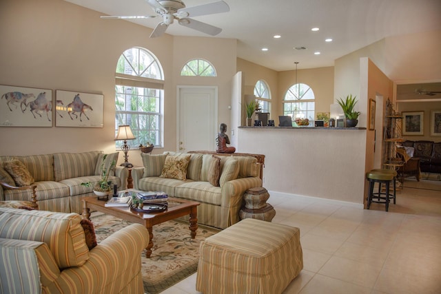 living room with a wealth of natural light, ceiling fan, a high ceiling, and light tile patterned flooring