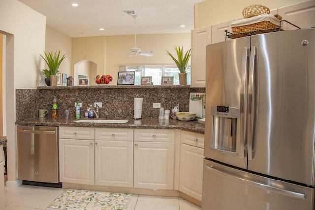 kitchen with dark stone counters, sink, light tile patterned floors, tasteful backsplash, and stainless steel appliances