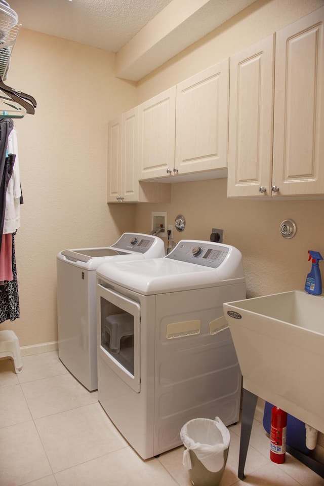 laundry area with cabinets, light tile patterned floors, and washing machine and dryer