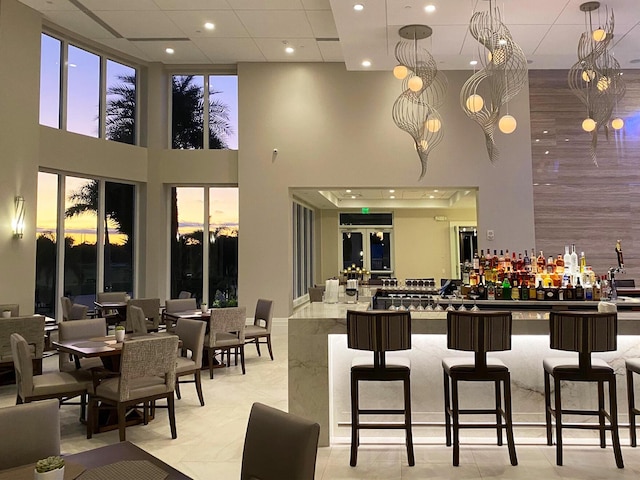 bar featuring a high ceiling and decorative light fixtures