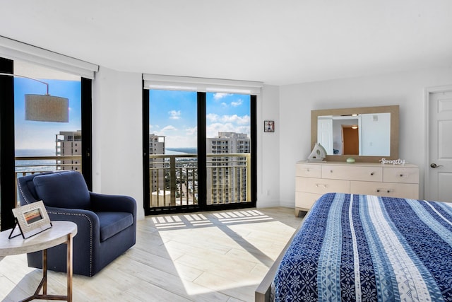 bedroom with light wood-type flooring, access to outside, and floor to ceiling windows