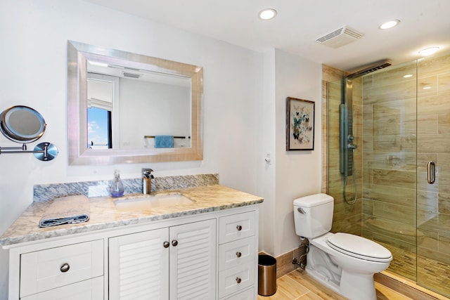 bathroom featuring vanity, toilet, and a shower with shower door