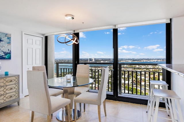 tiled dining room featuring expansive windows, a water view, and an inviting chandelier