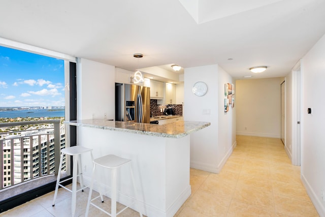 kitchen featuring kitchen peninsula, stainless steel fridge with ice dispenser, white cabinets, and decorative light fixtures