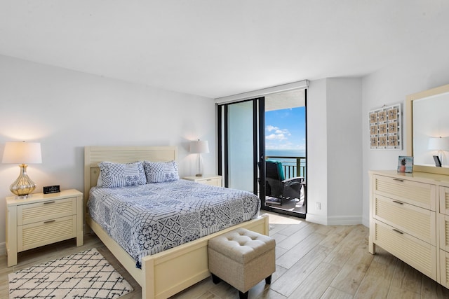 bedroom featuring access to exterior, light hardwood / wood-style flooring, and expansive windows