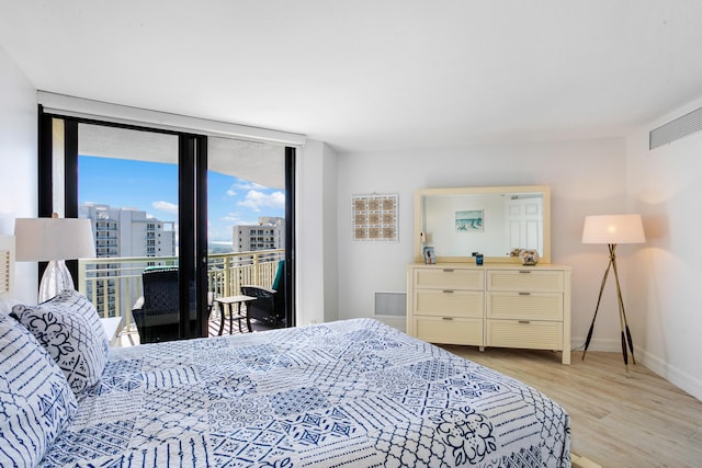 bedroom featuring light wood-type flooring, access to outside, and expansive windows