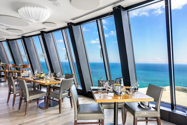 dining space featuring floor to ceiling windows, plenty of natural light, and a water view