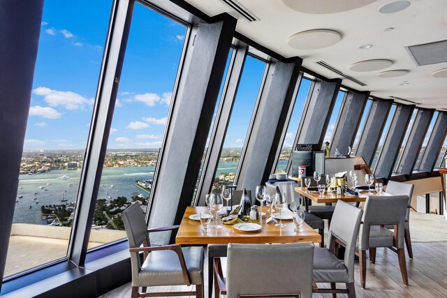 dining room featuring a water view, floor to ceiling windows, and hardwood / wood-style flooring