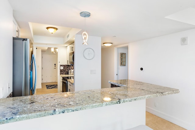 kitchen with kitchen peninsula, appliances with stainless steel finishes, light stone countertops, tasteful backsplash, and pendant lighting