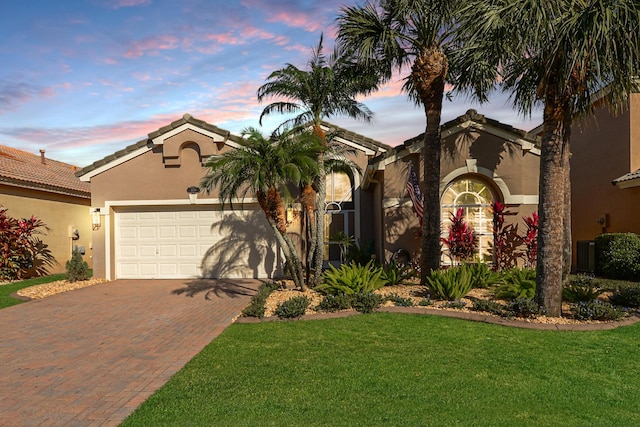 mediterranean / spanish-style home featuring a garage and a yard