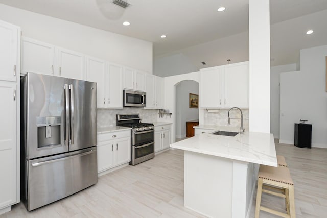 kitchen with kitchen peninsula, stainless steel appliances, white cabinetry, and sink