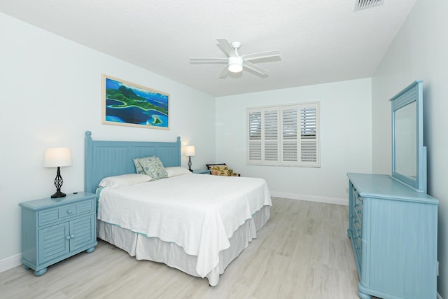 bedroom with ceiling fan, light hardwood / wood-style floors, and a textured ceiling