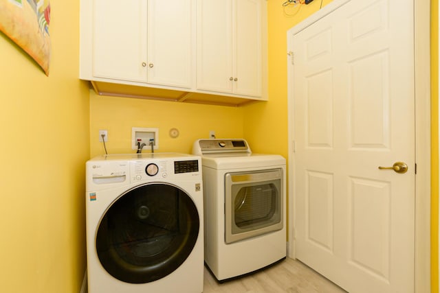 washroom with cabinets, light wood-type flooring, and separate washer and dryer