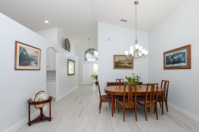 dining space with light hardwood / wood-style flooring, high vaulted ceiling, and a notable chandelier