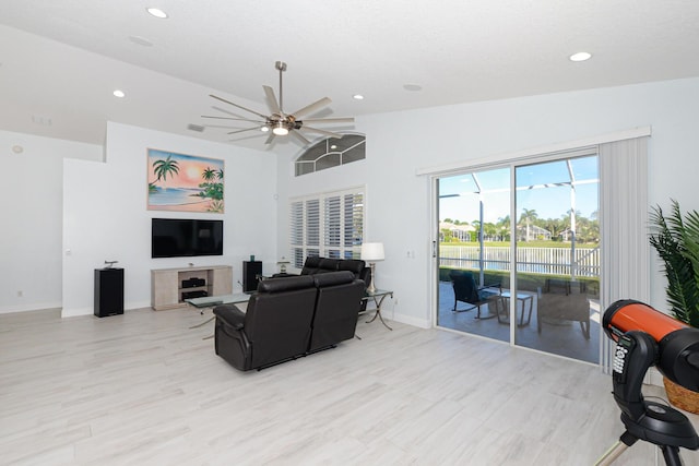 living room with ceiling fan, light hardwood / wood-style floors, and lofted ceiling