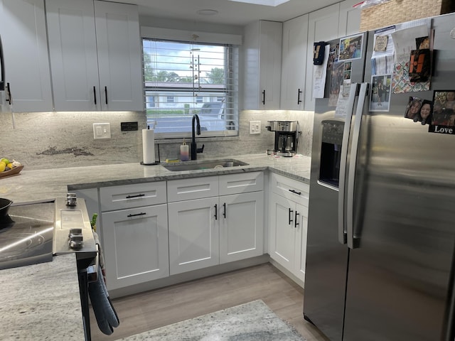 2864 Crosley Dr E Unit A, West Palm Beach, FL 33415 - kitchen with backsplash, white cabinetry, a sink, stainless steel fridge with ice dispenser, and light wood-style flooring