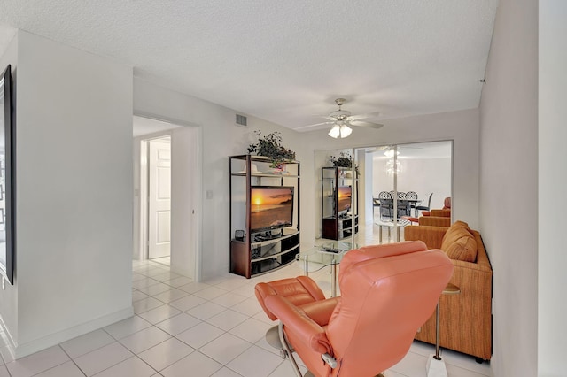 living room featuring ceiling fan, light tile patterned floors, and a textured ceiling