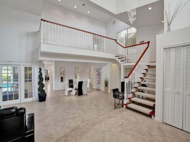 tiled entrance foyer with a towering ceiling and a chandelier