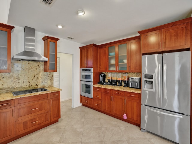 kitchen with tasteful backsplash, light stone countertops, stainless steel appliances, and wall chimney range hood