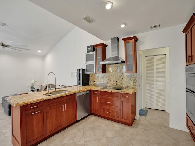 kitchen with kitchen peninsula, stainless steel appliances, ceiling fan, sink, and wall chimney range hood