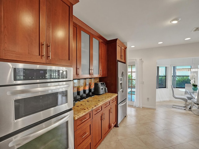 kitchen with light stone countertops, light tile patterned floors, stainless steel appliances, and decorative backsplash