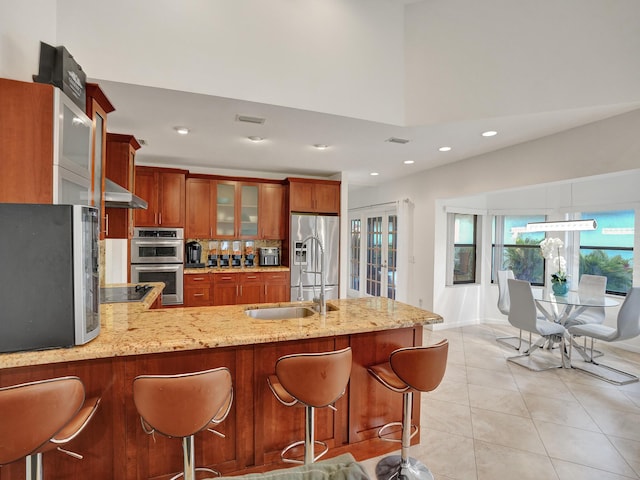 kitchen featuring kitchen peninsula, a kitchen bar, ventilation hood, stainless steel appliances, and light tile patterned floors