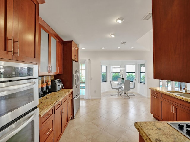 kitchen featuring light stone countertops, appliances with stainless steel finishes, decorative backsplash, sink, and light tile patterned floors