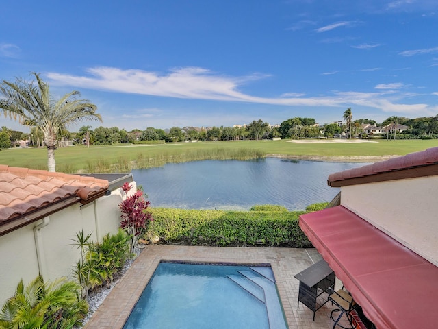 view of pool featuring a lawn, a patio area, and a water view