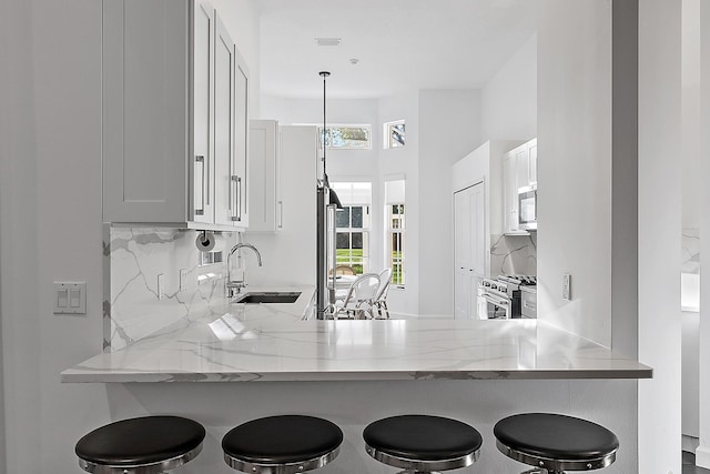 kitchen featuring decorative light fixtures, white cabinetry, stainless steel appliances, and a breakfast bar area