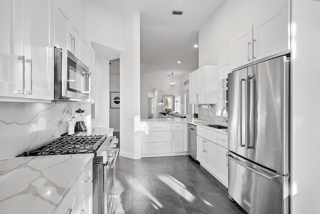 kitchen featuring tasteful backsplash, light stone counters, sink, high quality appliances, and white cabinetry