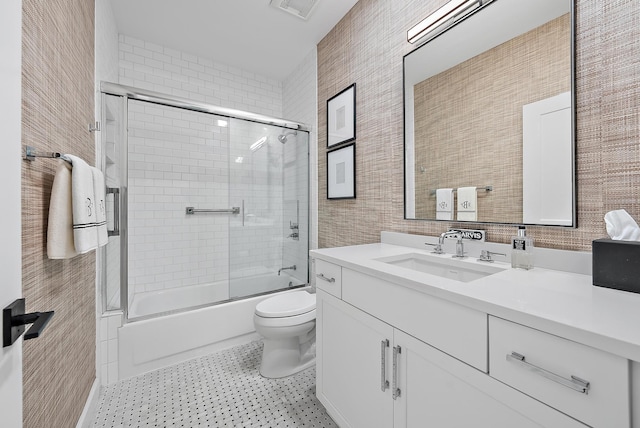 full bathroom with vanity, bath / shower combo with glass door, and toilet