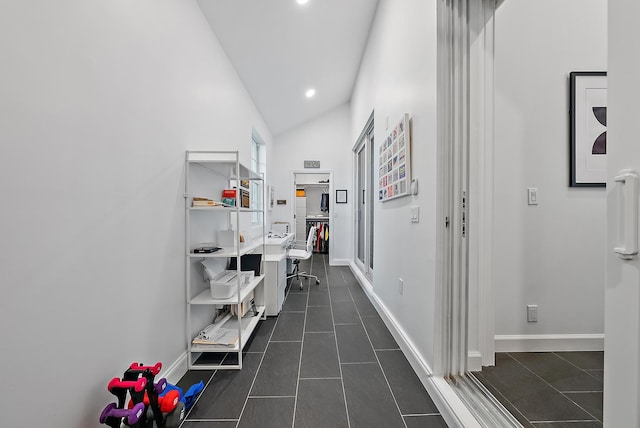 corridor with dark tile patterned flooring and vaulted ceiling