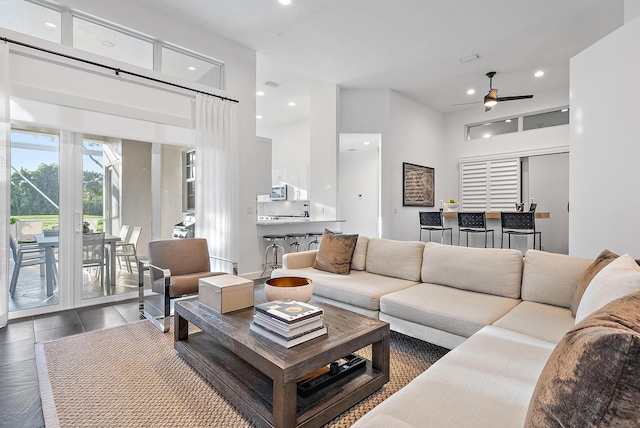 living room featuring ceiling fan and a towering ceiling