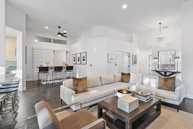 living room featuring ceiling fan with notable chandelier and a towering ceiling